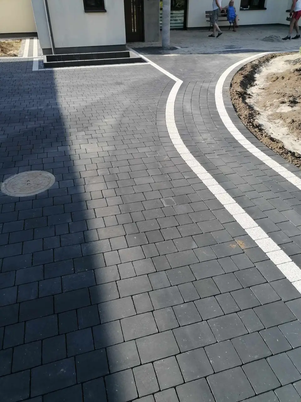 Podjazd z łukowym jasnym pasem z kostki