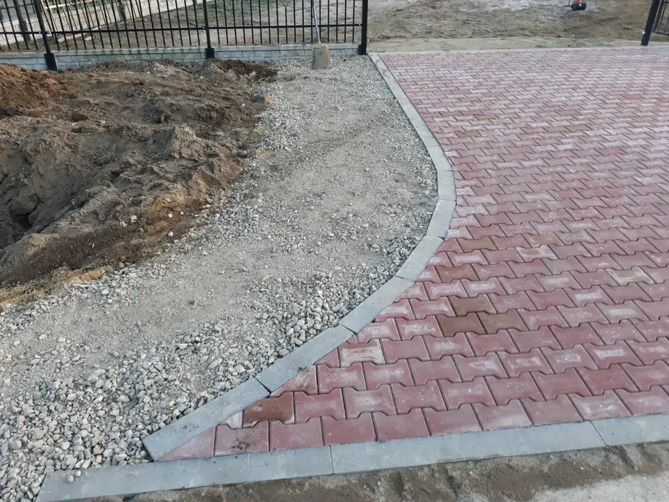 Wjazd z czerwonej i szarej kostki z obrzeżami przy drodze